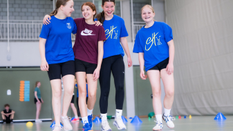 Vier junge Frauen in Sportkleidung in einer Halle
