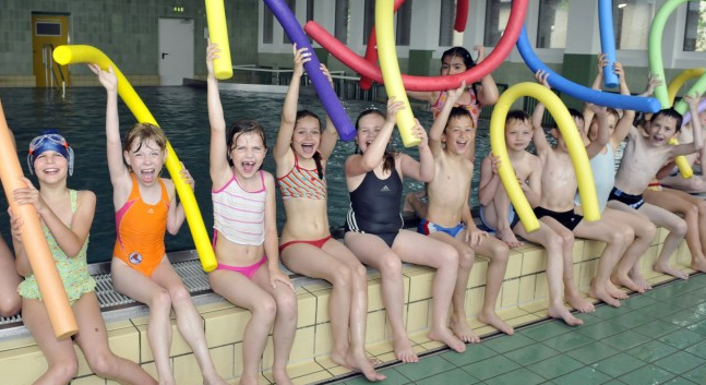 Kinder mit Schwimmnudeln im Schwimmbad